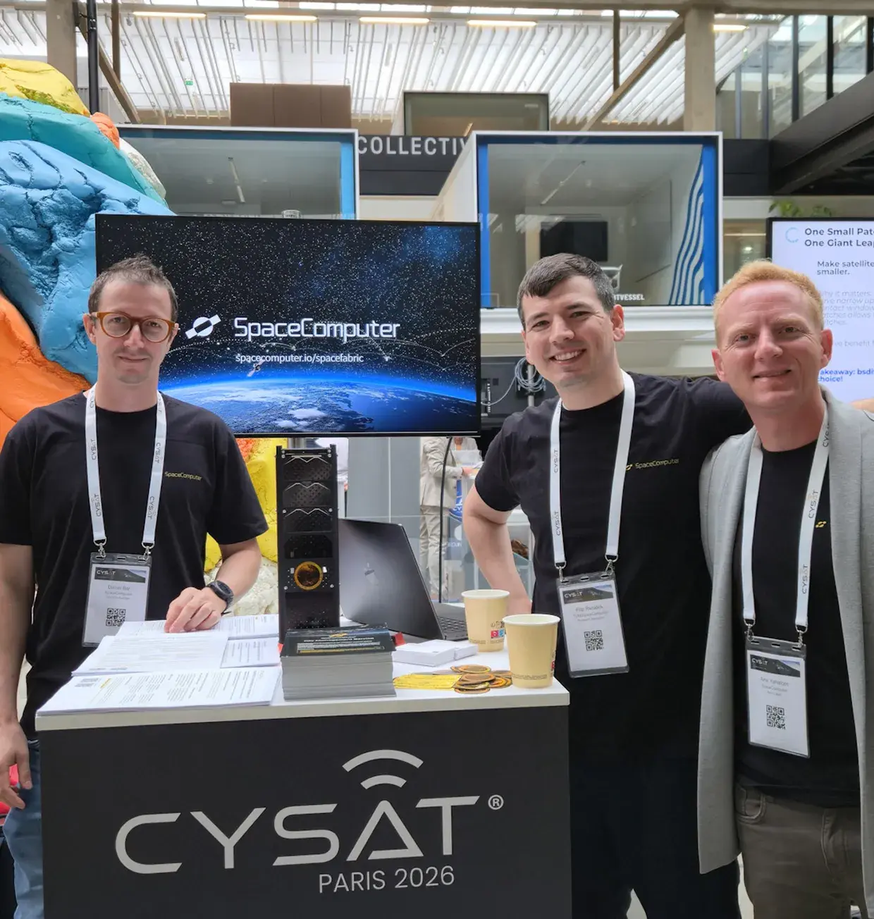 SpaceComputer booth at CYSAT Paris with team members and a demo screen